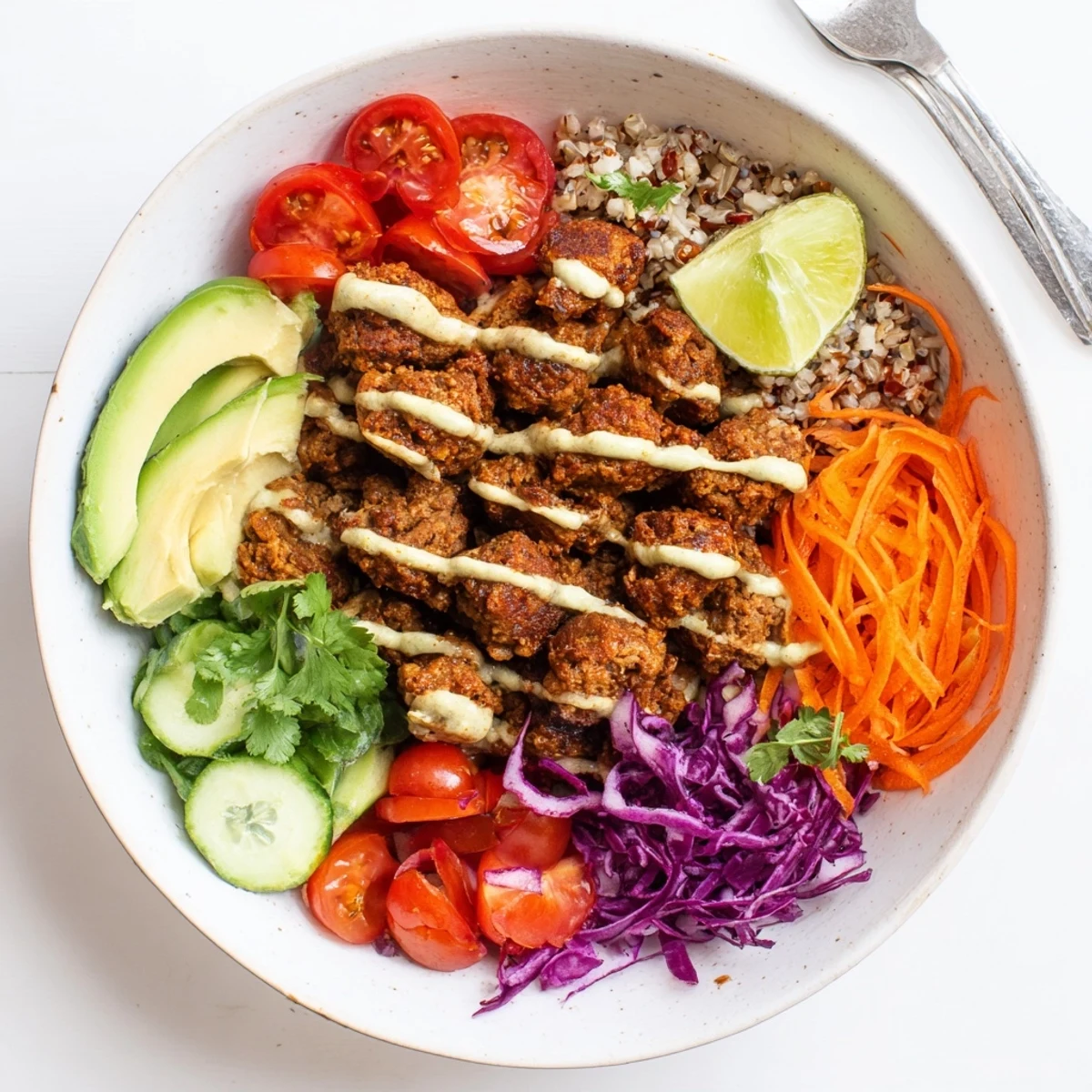Satisfying plant-based meat bowl served with creamy sriracha sauce and sliced avocado.