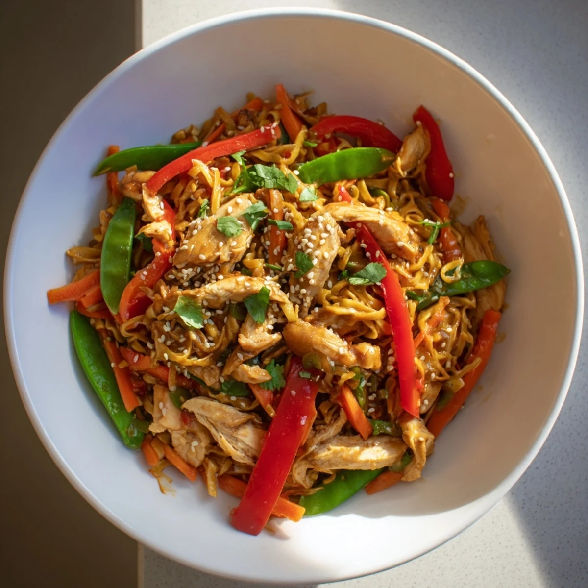A steaming bowl of Lemon-Garlic Chicken Stir Fry shows glistening noodles and colorful vegetables.