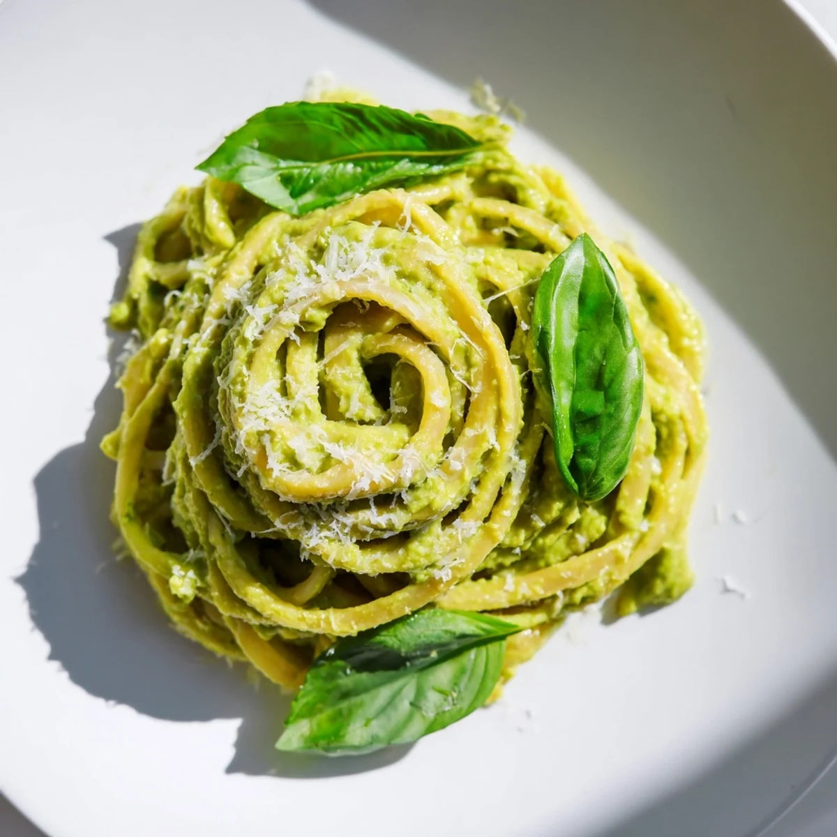 Creamy avocado pasta, glistening with a vibrant avocado sauce, ready to be devoured with fresh basil.