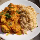 A close-up shot of butter chicken served alongside fluffy rice pilaf, a truly comforting meal.