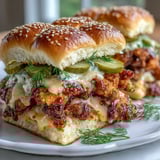 A close-up of the Spicy Honey Butter Chicken Sandwich Bake shows melted cheese and toasted sesame bun tops, ready to be pulled apart for a delicious game day appetizer.