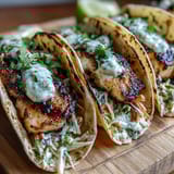Grilled coconut lime fish tacos with fresh cabbage slaw and tangy crema on warm tortillas.  