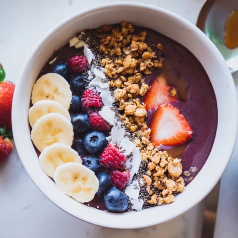 A vibrant Acai Bowl: Sweet frozen fruit, crunchy granola, and drizzled honey create a delightful texture.