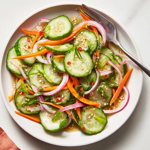 Fresh cucumber salad remix topped with sesame seeds and vibrant vegetable slices.  