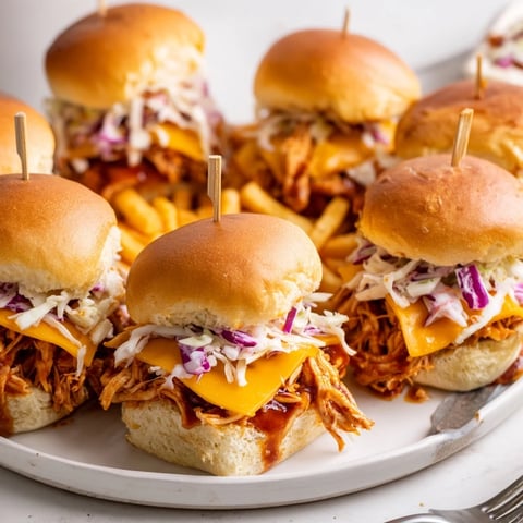 Juicy BBQ chicken sliders piled high with coleslaw and melted cheddar cheese.  