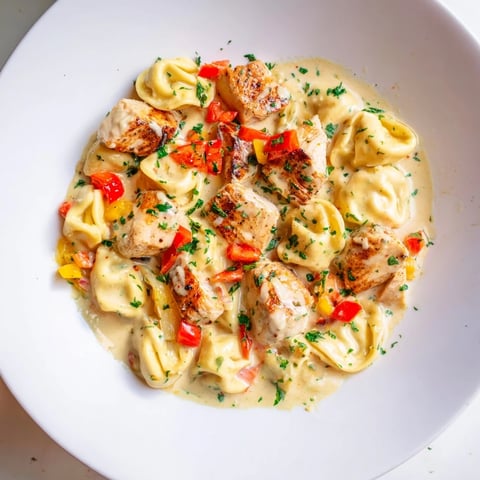 Zesty Cajun Garlic Parmesan Chicken Tortellini: creamy pasta dish with chicken, peppers, and parsley garnish.