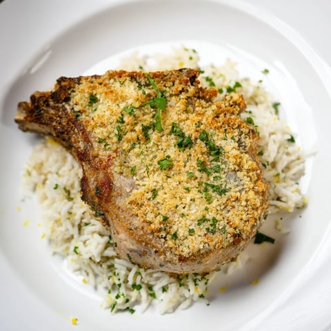 Golden-crusted Parmesan Herb Pork Chops nestled atop fluffy rice, a comforting American dinner.