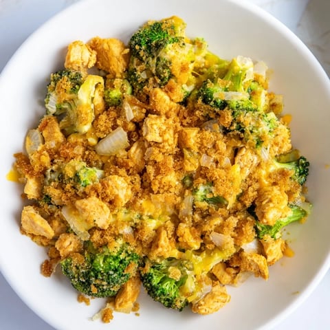 Golden, bubbly Cheddar Broccoli Chicken Bake, smelling savory, ready to be scooped onto plates.
