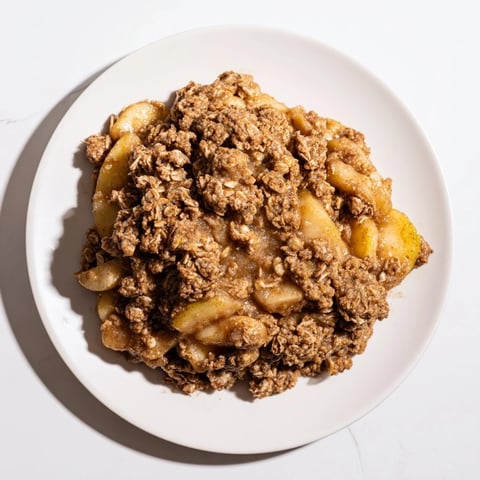 Golden brown apple crisp with warm, bubbly fruit filling, a delicious dessert served with vanilla ice cream.