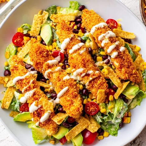 Crispy Chicken Taco Salad with golden fried chicken strips on a bed of fresh romaine lettuce and diced avocado.