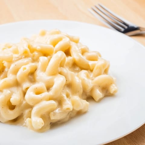 A bowl of high-protein mac & cheese featuring smooth cottage cheese blend and herbs.  