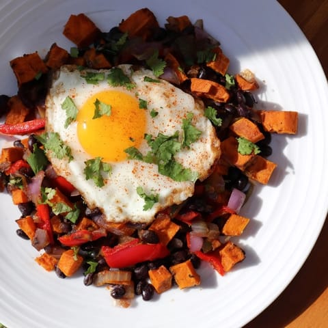 A skillet is filled with the vibrant Sweet Potato & Black Bean Breakfast Hash, ready to be enjoyed.