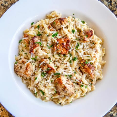 This photo shows a bubbling One-Pot Cajun Chicken Alfredo Orzo, ready to serve with Parmesan garnish.