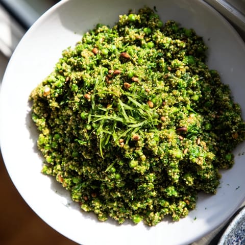 A bowl of colorful, protein-packed Green Pea & Spinach Pasta, topped with lemon zest and pine nuts.