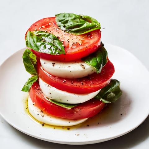 Fresh Sliced Tomatoes and Mozzarella Rounds, a colorful appetizer arranged with vibrant basil.
