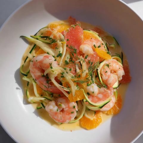 A beautiful, colorful The Coral Reef dish features shrimp, citrus fruit, and melted Gruyère cheese.