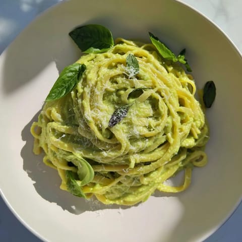 Delicious creamy avocado pasta, perfectly coated in the bright green sauce, garnished with Parmesan cheese and basil.
