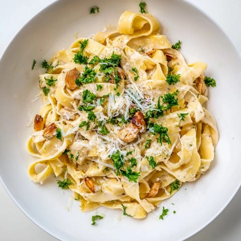 The finished Roasted Garlic Cream Pasta served warm in a white bowl, garnished with fresh parsley and extra grated Parmesan for a comforting meal.