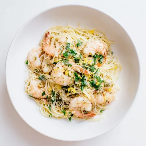 Savory Lemon Butter Shrimp Pasta Lite is served in a white bowl, garnished with lemon wedges for a bright finish.  