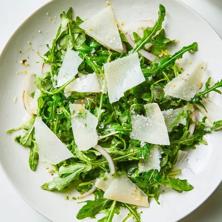 Close-up of the flavorful arugula salad with vibrant lemon dressing and shaved Parmesan.